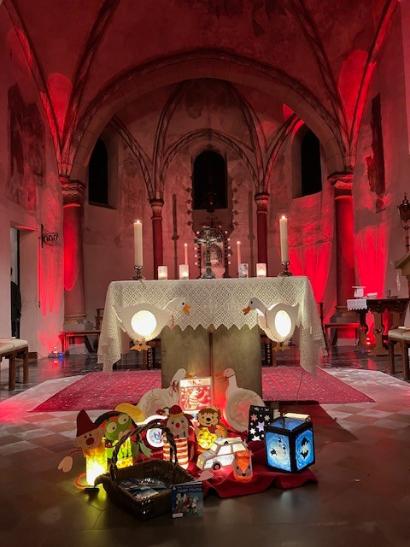 Selbstgebastelte Laternen stehen aufgebaut vor dem Altar in einer Kirche